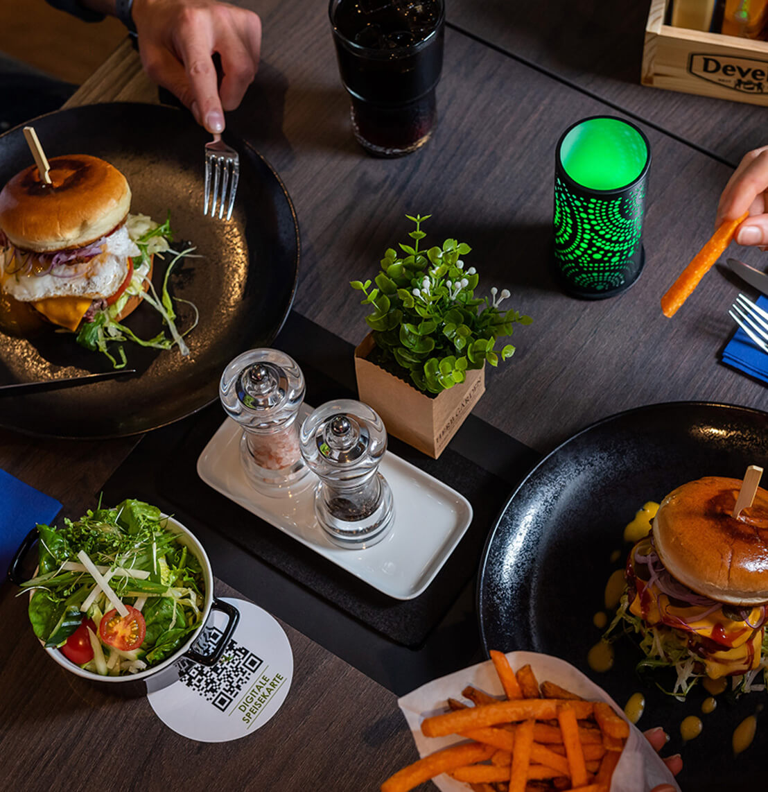 Gedeckter Tisch mit Burger, Toppings und Getränken